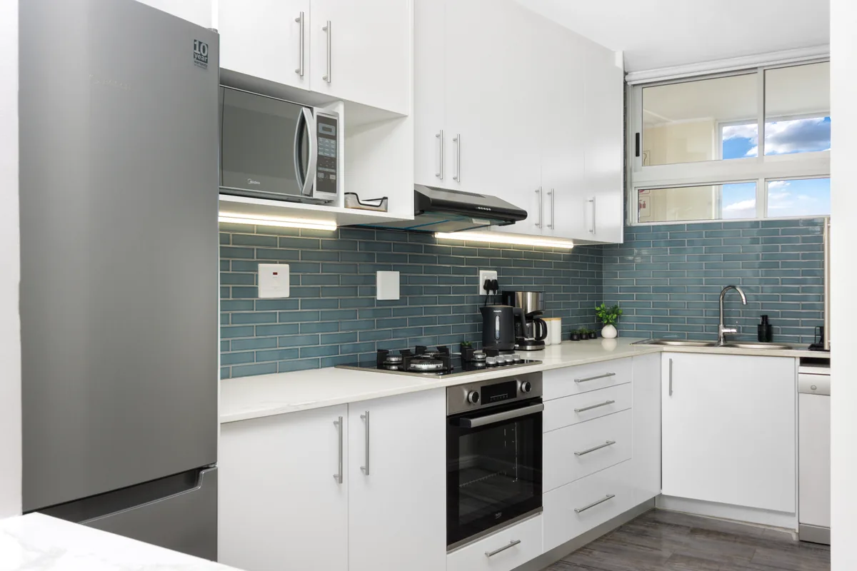 Fully equipped white kitchen with distinctive deep-blue tiles